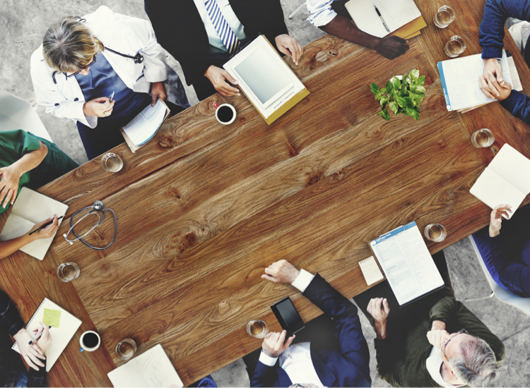 Meeting with doctors and business people around a table to represent A Market Researcher’s Guide to Clinical Commissioning Groups