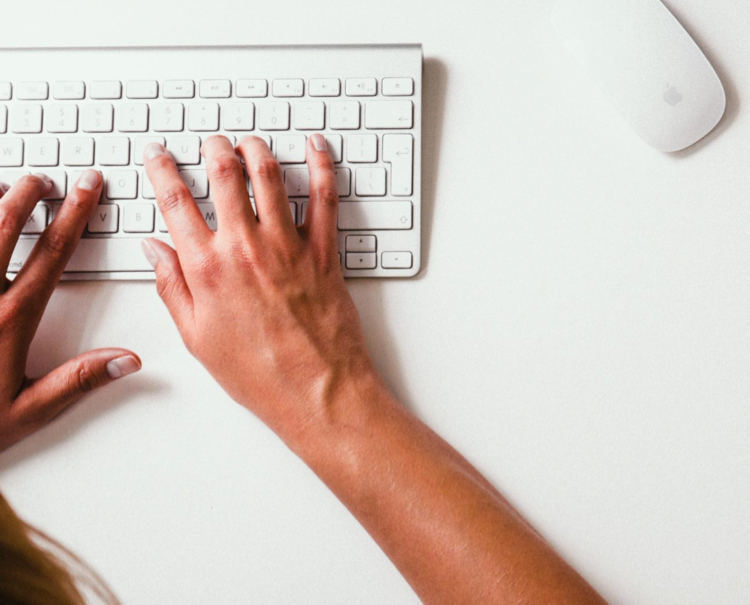 Man's hands typing on a Mac keyboard