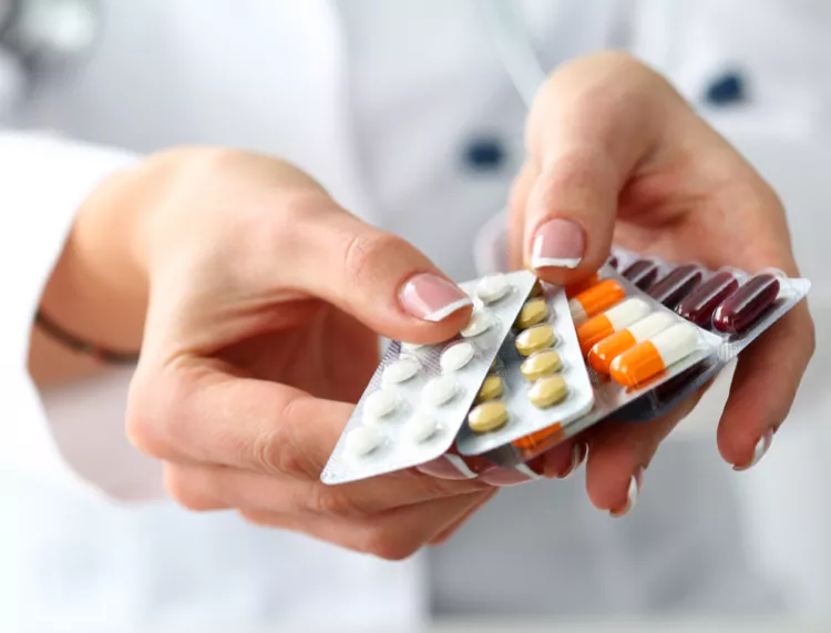 Person in a white coat holding out an array of pills - Patient market research